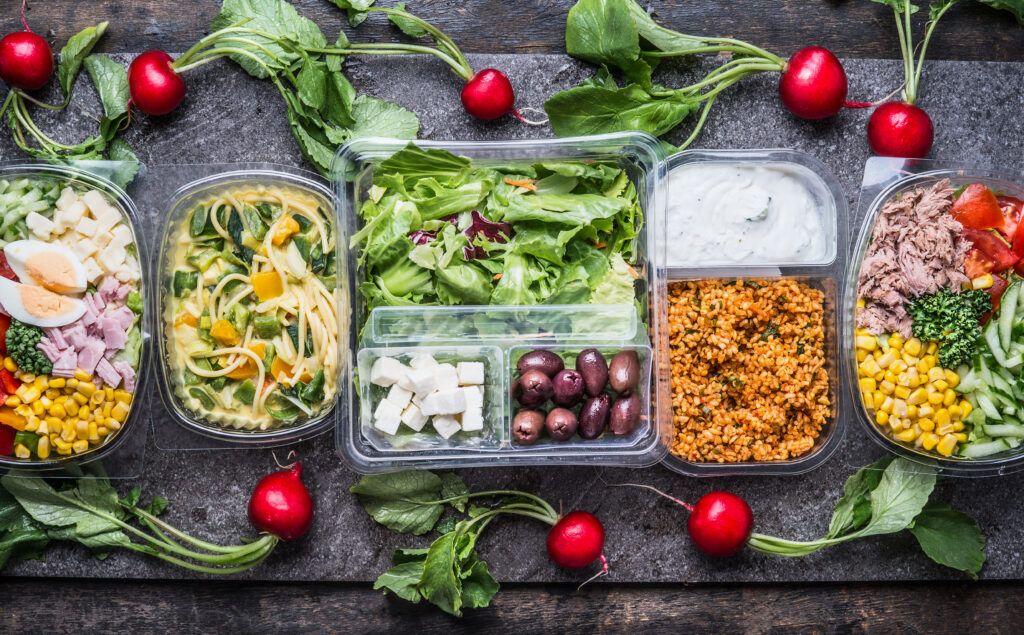 Variety of foods shown packaged in clear plastic thermoformed containers