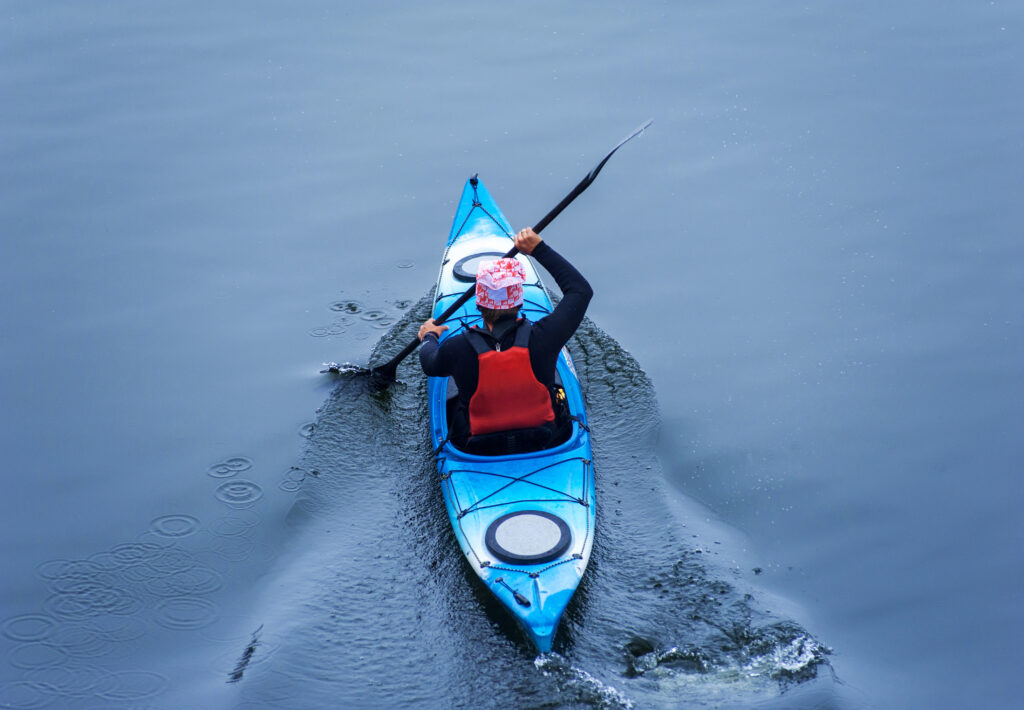 Man paddling in a blue kayak on a river