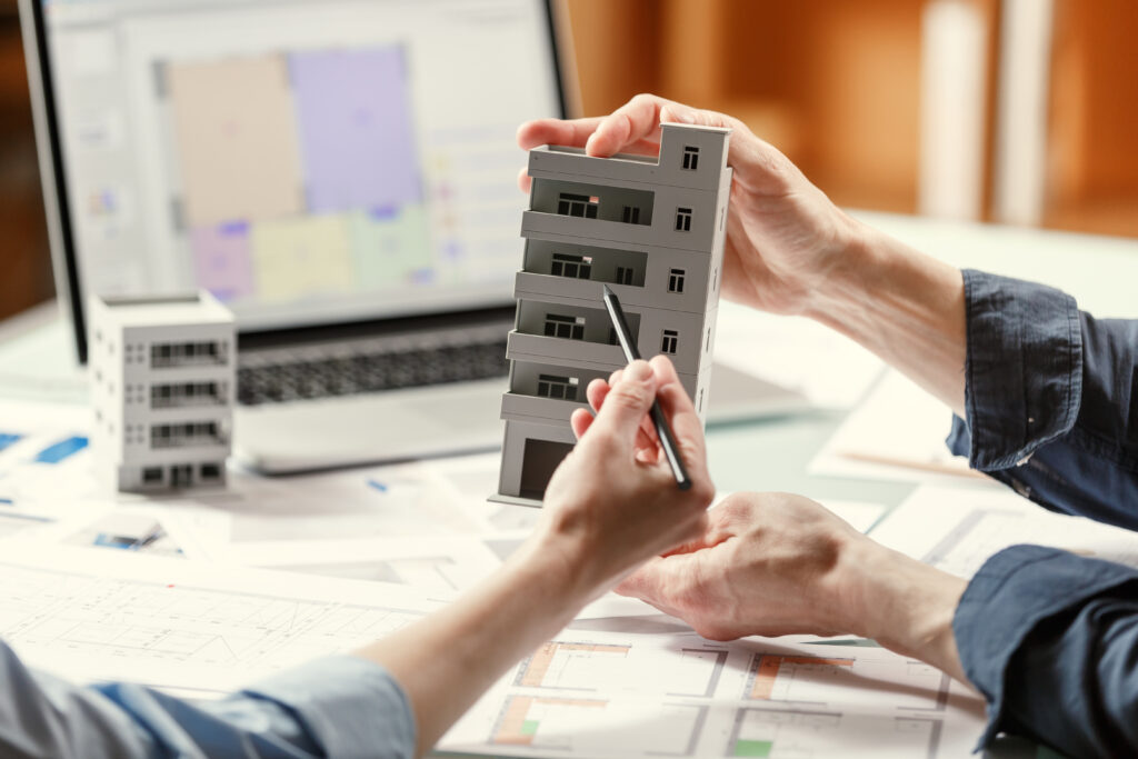 Two architects holding a composite model of a building