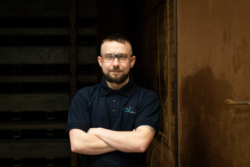 Base Materials employee standing with arms crossed wearing safety goggles