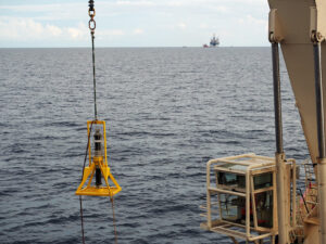 Subsea beacon being lifted out of the water by vessel crane