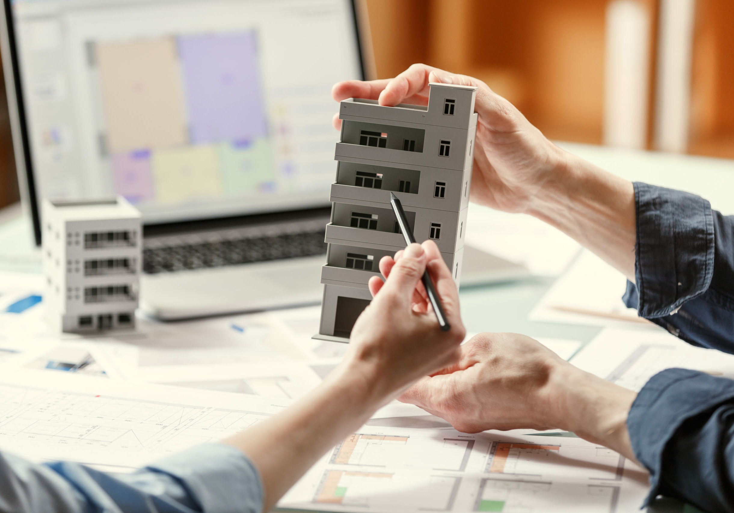 Two architects holding a composite model of a building