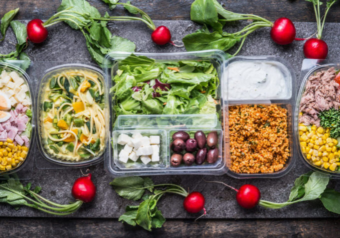 Variety of foods shown packaged in clear plastic thermoformed containers