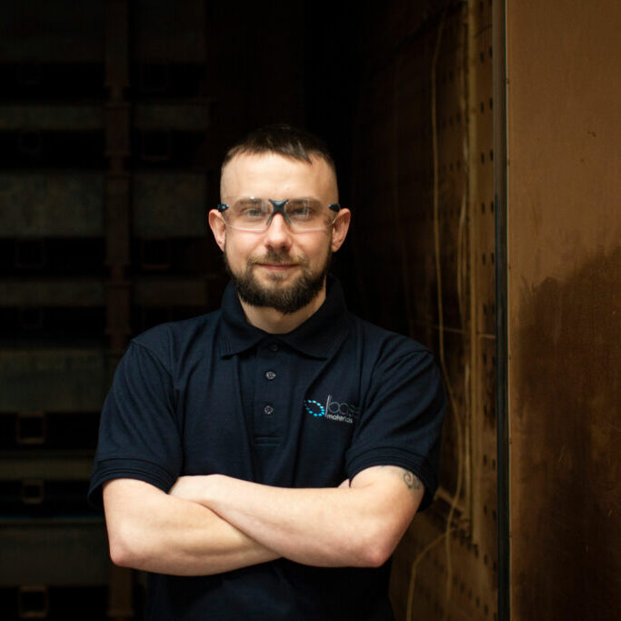 Base Materials employee standing with arms crossed wearing safety goggles