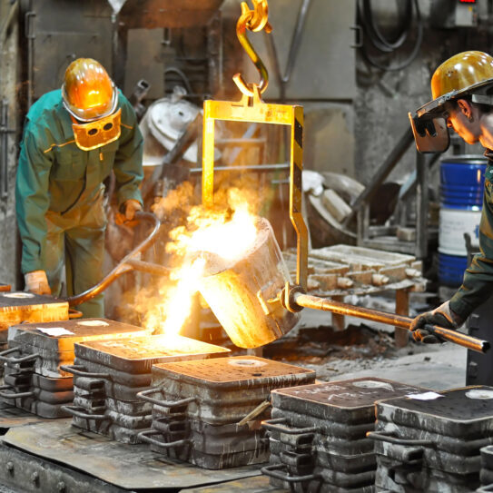 Group of workers in a foundry at the melting furnace